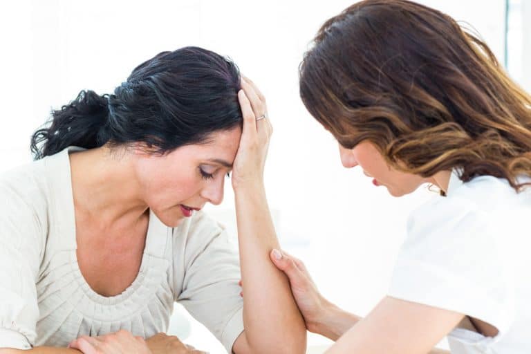 Therapist comforting her patient on white background