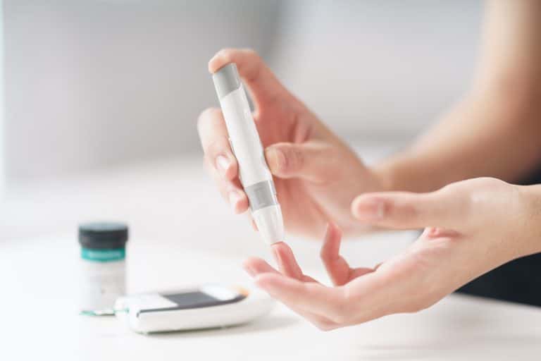 Asian woman using lancet on finger for checking blood sugar leve